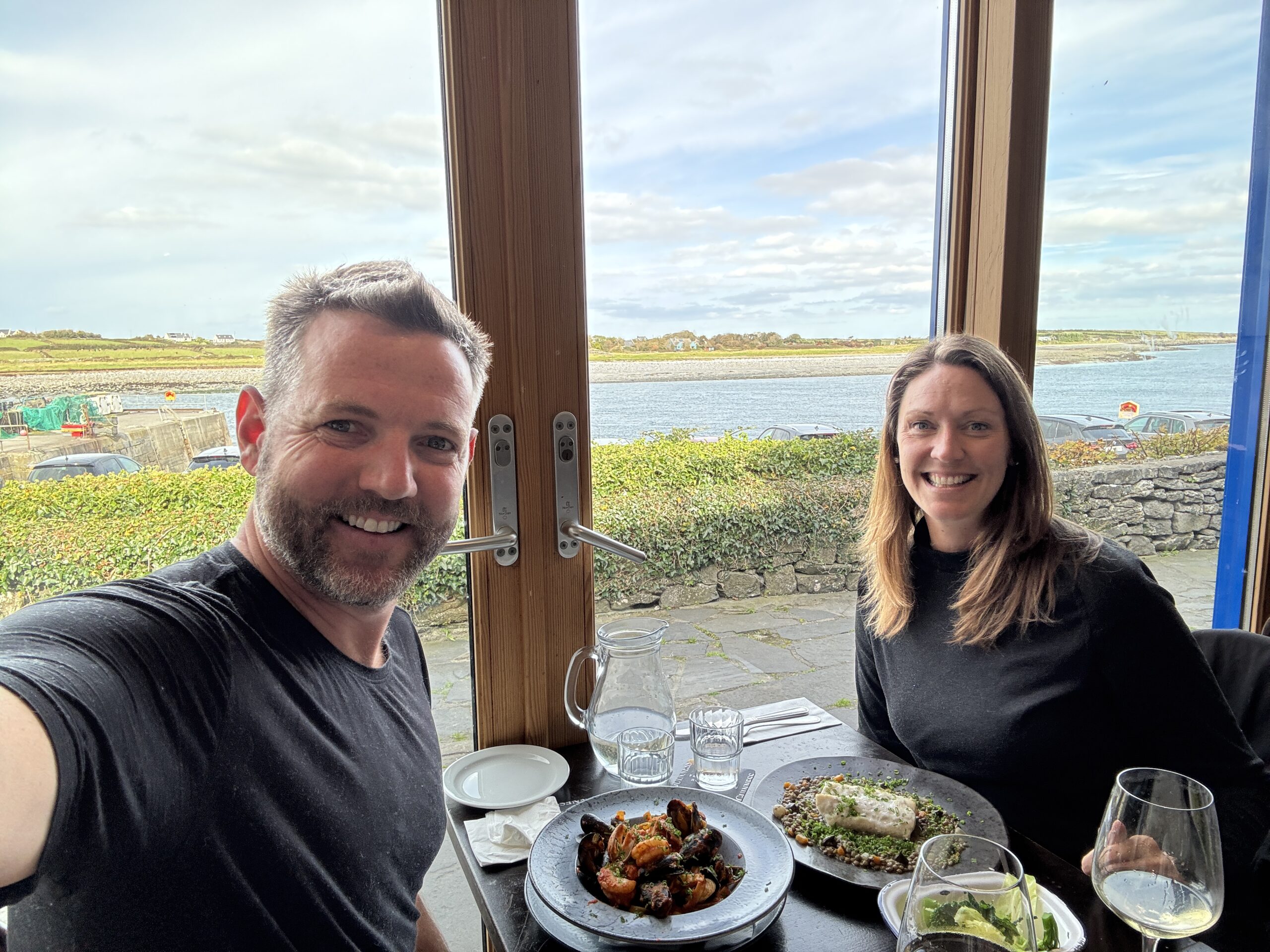 Couple enjoying seafood lunch with harbour view at restaurant on Aran Islands, Ireland