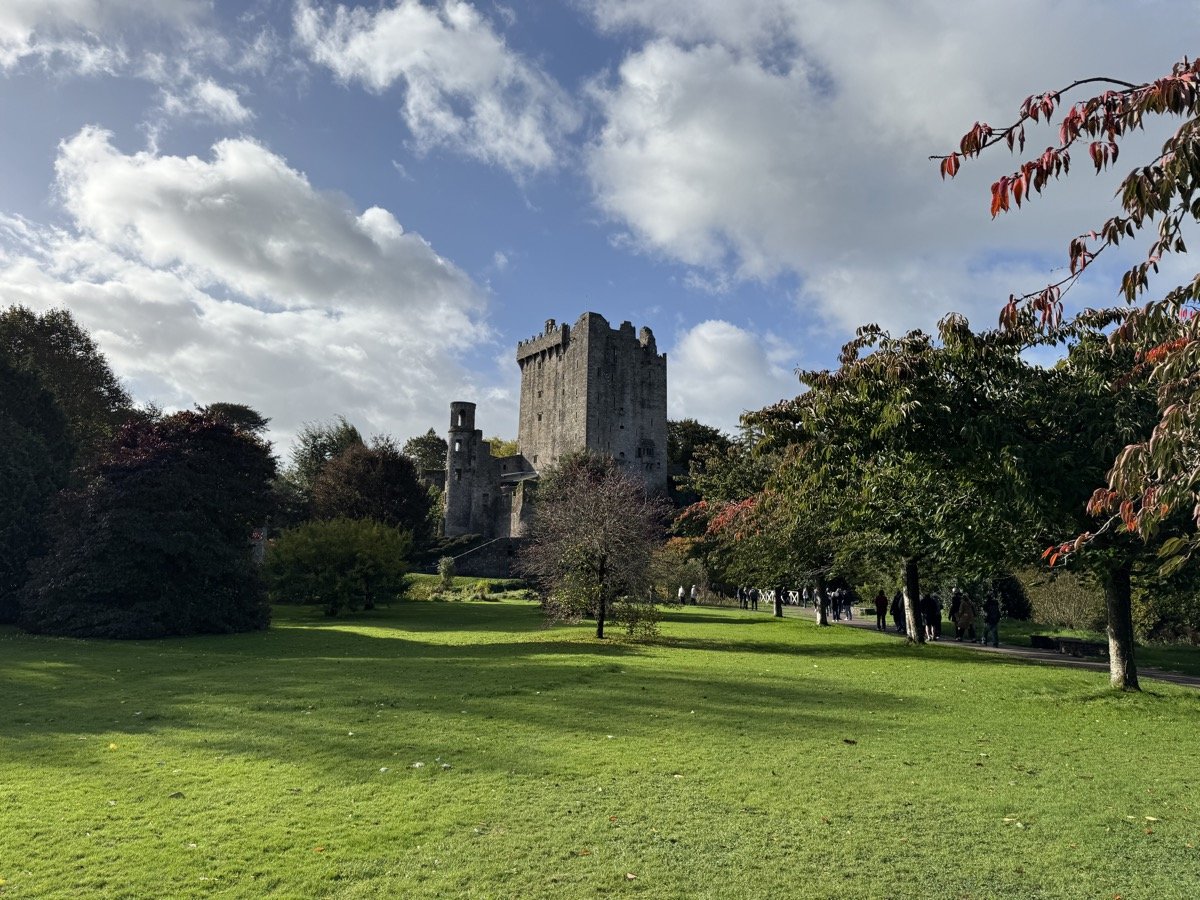 Blarney Castle medieval tower in Cork Ireland with autumn foliage and visitors on grounds