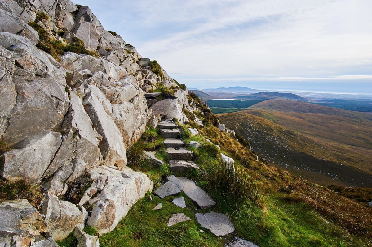 stone steps ascend a rocky mountain ridge above rolling highlands