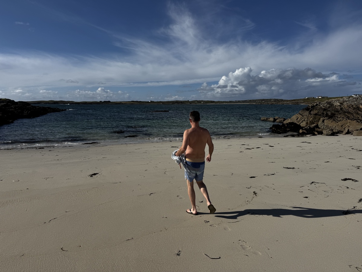 Nick walking toward the sea on a beach near Clifden