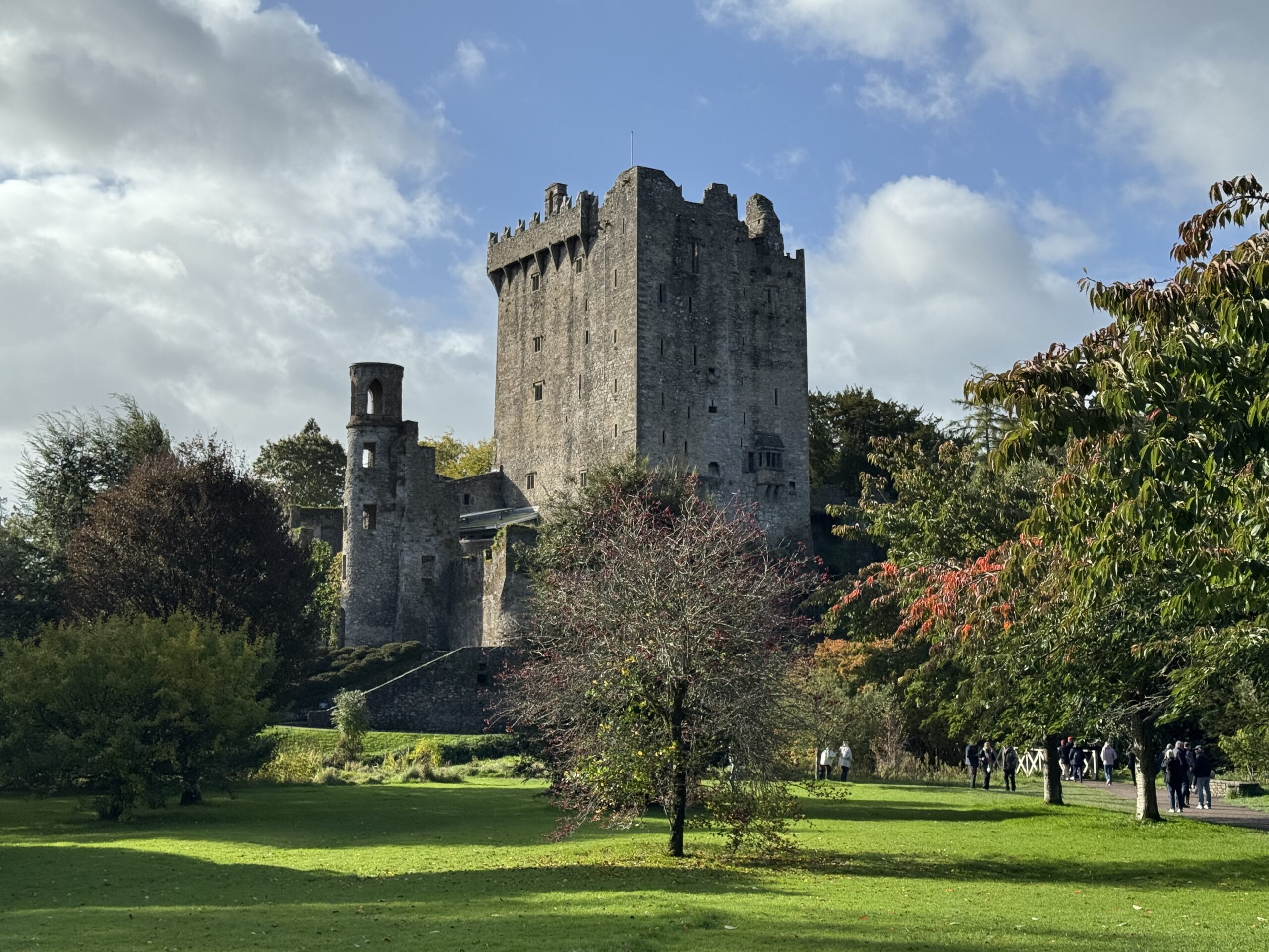 Blarney Castle tower and autumn trees with tourists in the grounds, Cork
