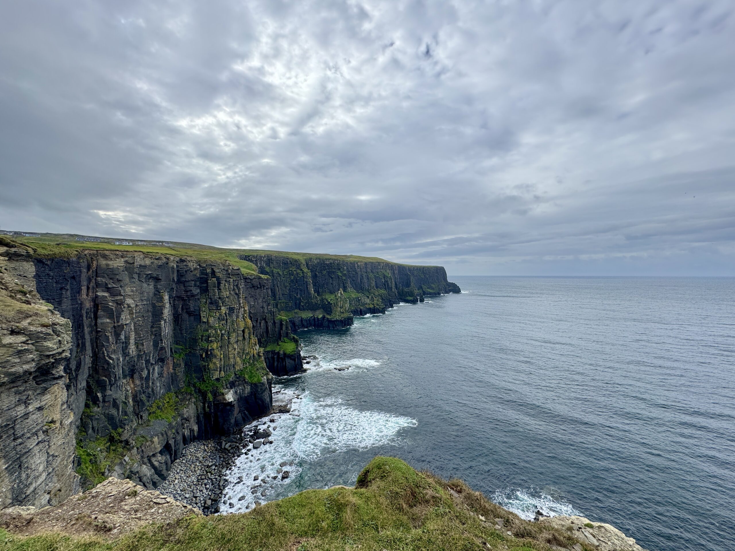 The Cliffs of Moher stretching along the Atlantic coastline under a cloudy sky, County Clare, Ireland