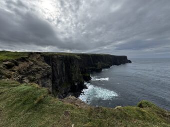 Dramatic Cliffs of Moher in County Clare Ireland with stormy clouds and Atlantic Ocean waves