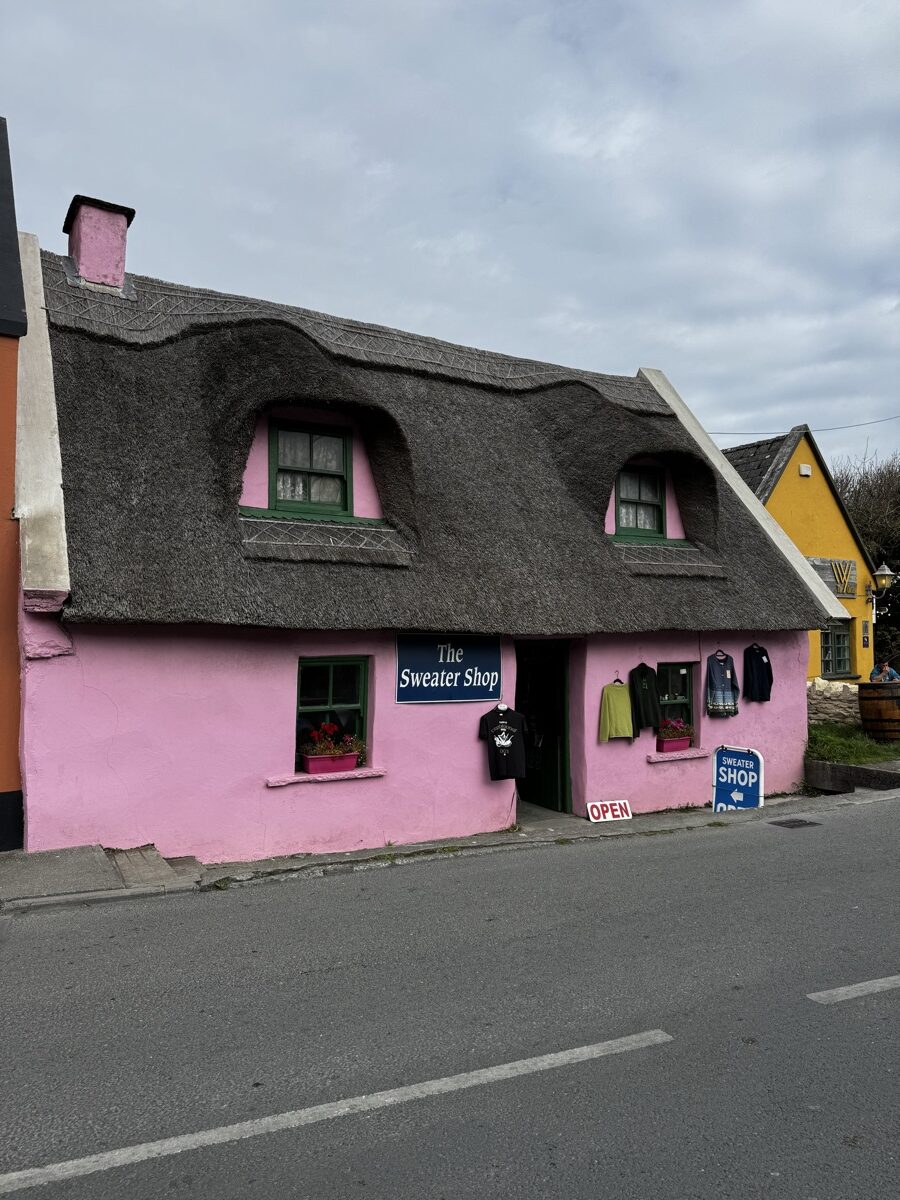 Bright pink thatched cottage sweater shop in a County Clare village, Ireland