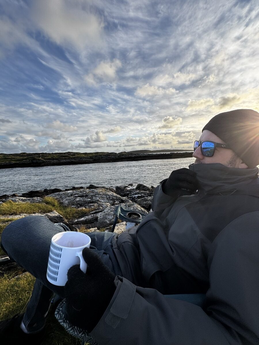 Nick with a coffee cup watching the Atlantic sunset from a rocky shore in Connemara, County Galway, Ireland