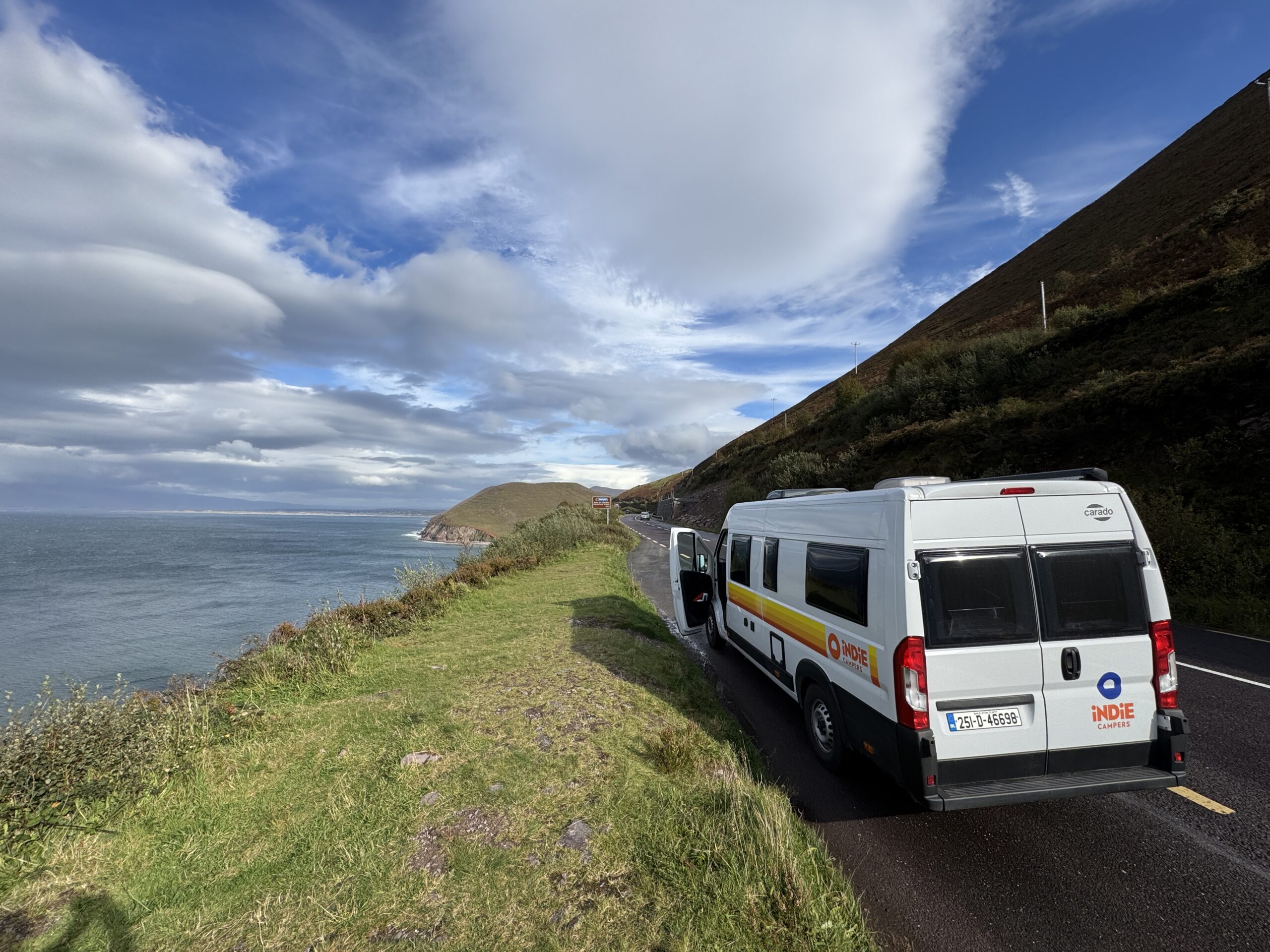 An Indie Campers van parked on the Ring of Kerry coastal road with dramatic mountain and Atlantic views