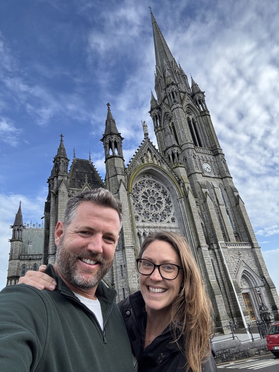 Couple smiling in selfie outside St. Colman's Cathedral in Cobh, County Cork, Ireland