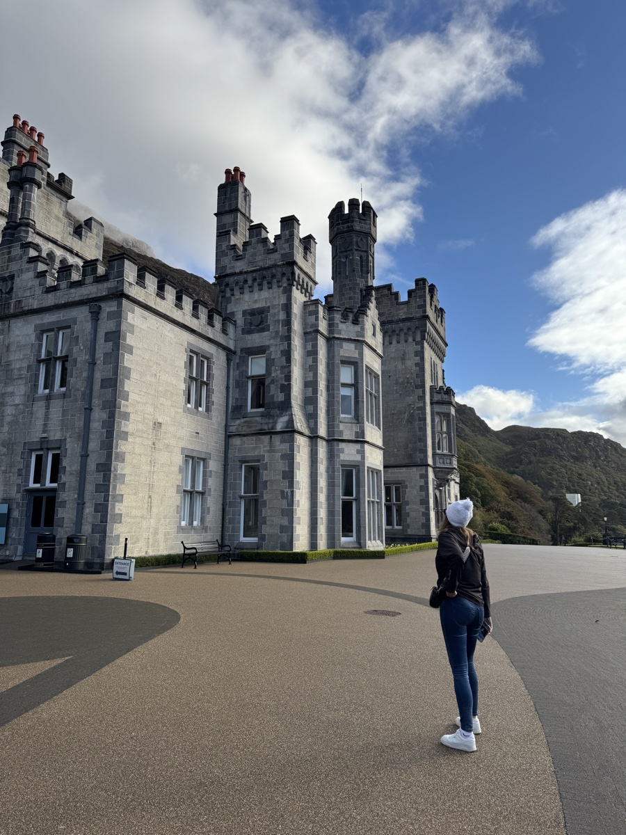 Dariece standing in front of the Gothic facade of Kylemore Abbey in Connemara, County Galway