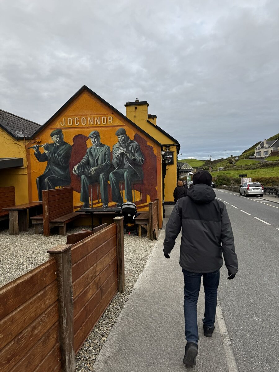 Nick walking along the main street in Doolin past the famous J. O'Connor's pub trad music mural