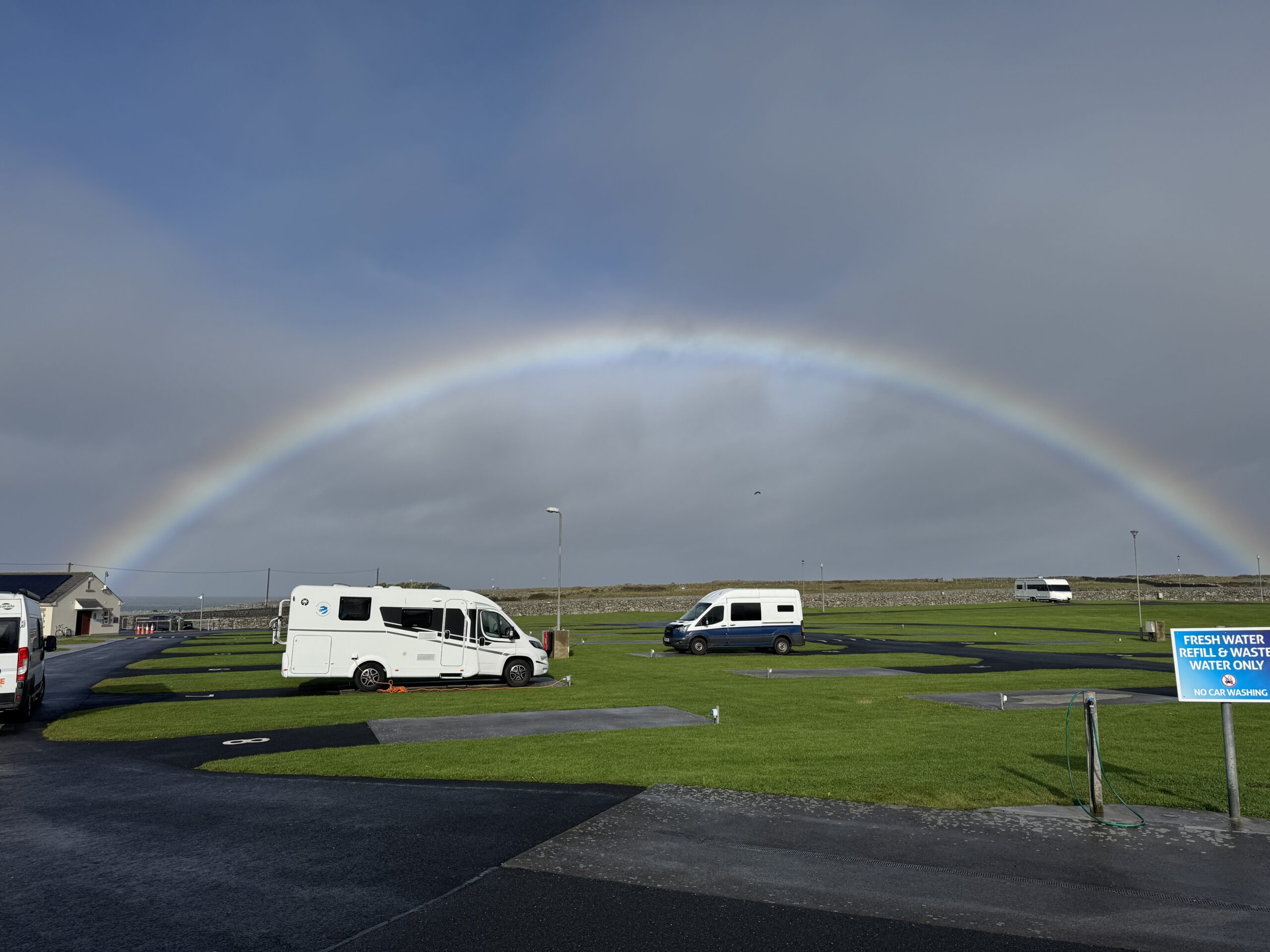Rainbow arching over Doolin motorhome campsite in County Clare, Ireland with parked campervans