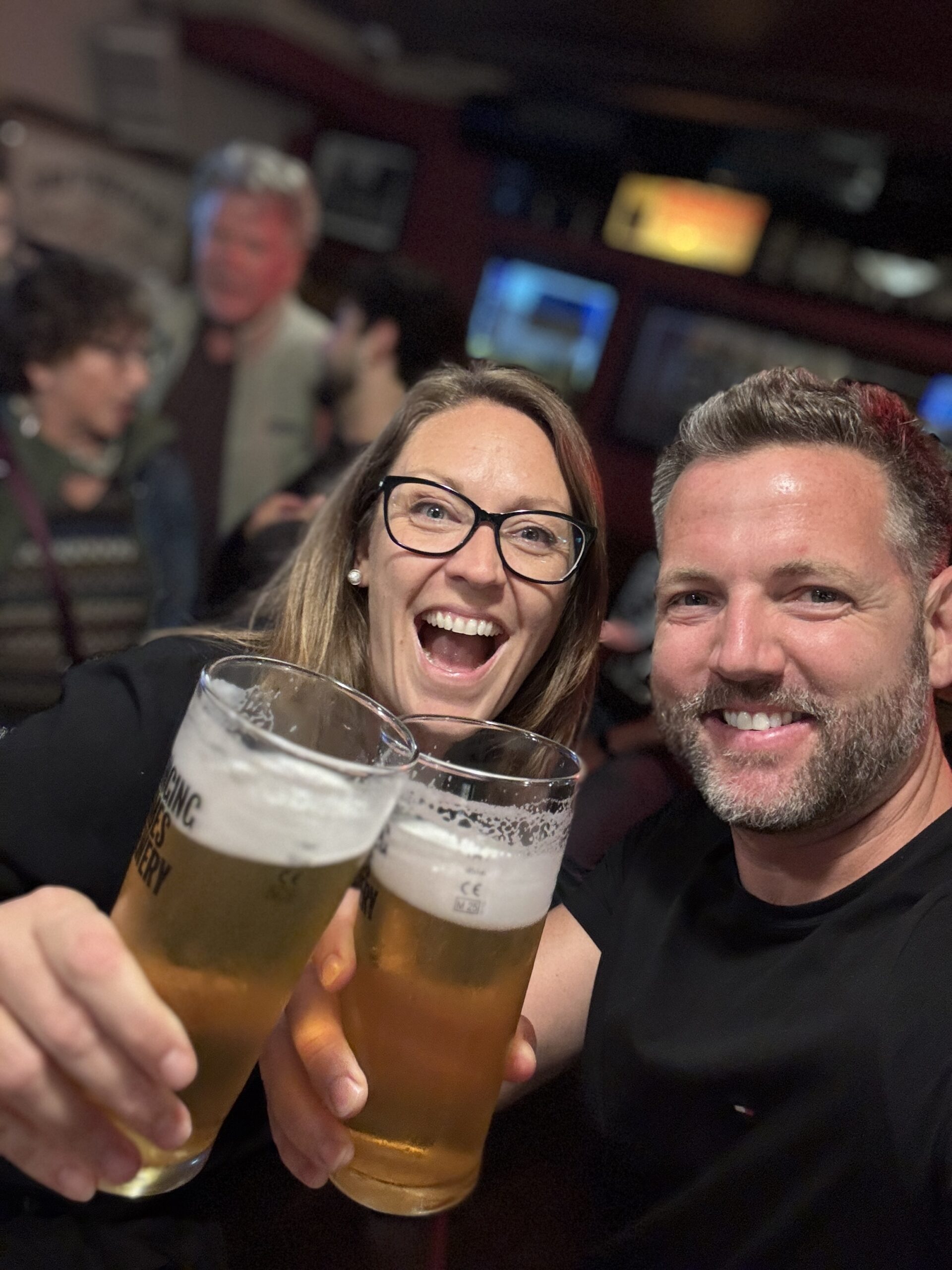 Couple toasting with large pints of beer in a busy Dublin pub, Ireland