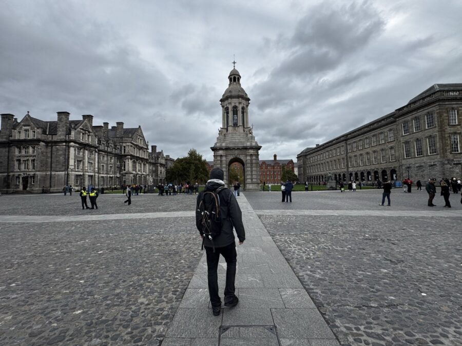 Walking toward the iconic Campanile bell tower in the cobbled Parliament Square at Trinity College Dublin