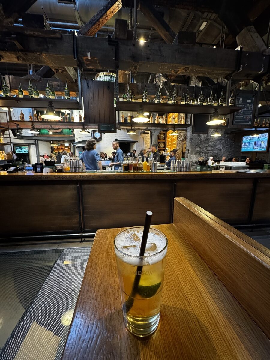 A pint of lager on a table in front of the rustic exposed beam bar of a Dublin pub