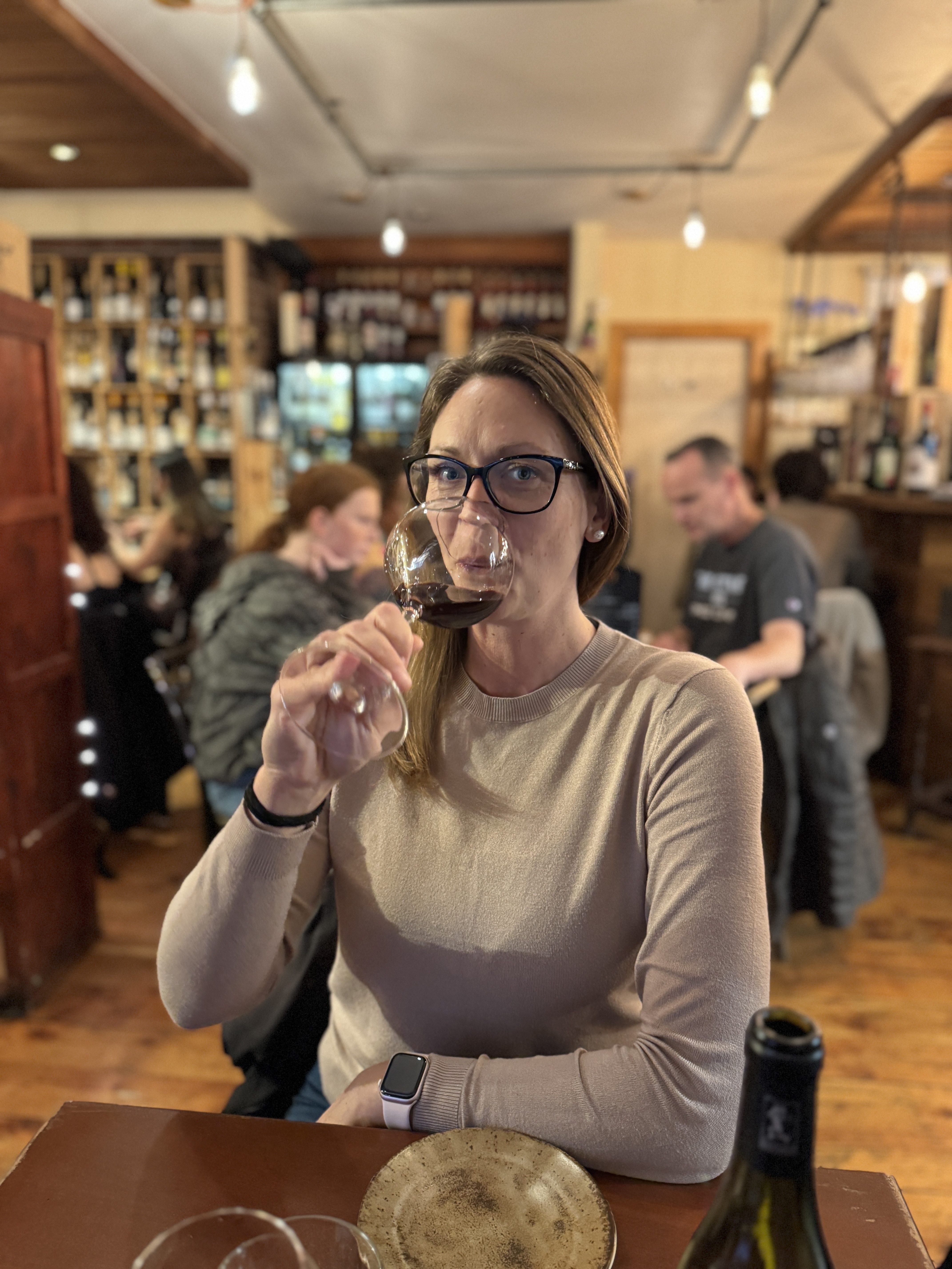 Woman tasting red wine at a busy wine bar in Dublin, Ireland