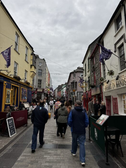 Busy pedestrian street in Galway's Latin Quarter with colourful shopfronts and crowds, Ireland