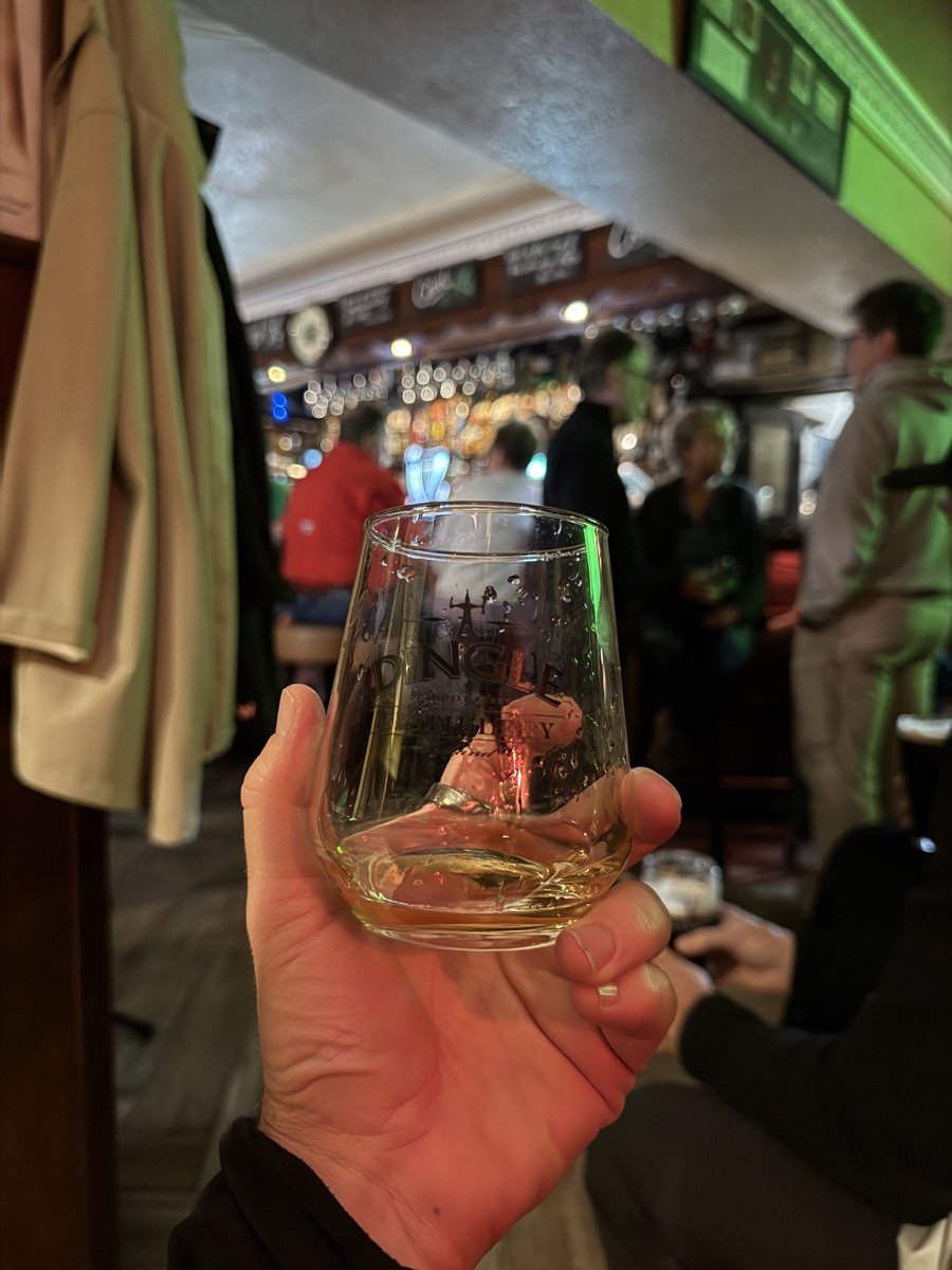 Hand holding a whiskey glass in a traditional Kerry pub interior