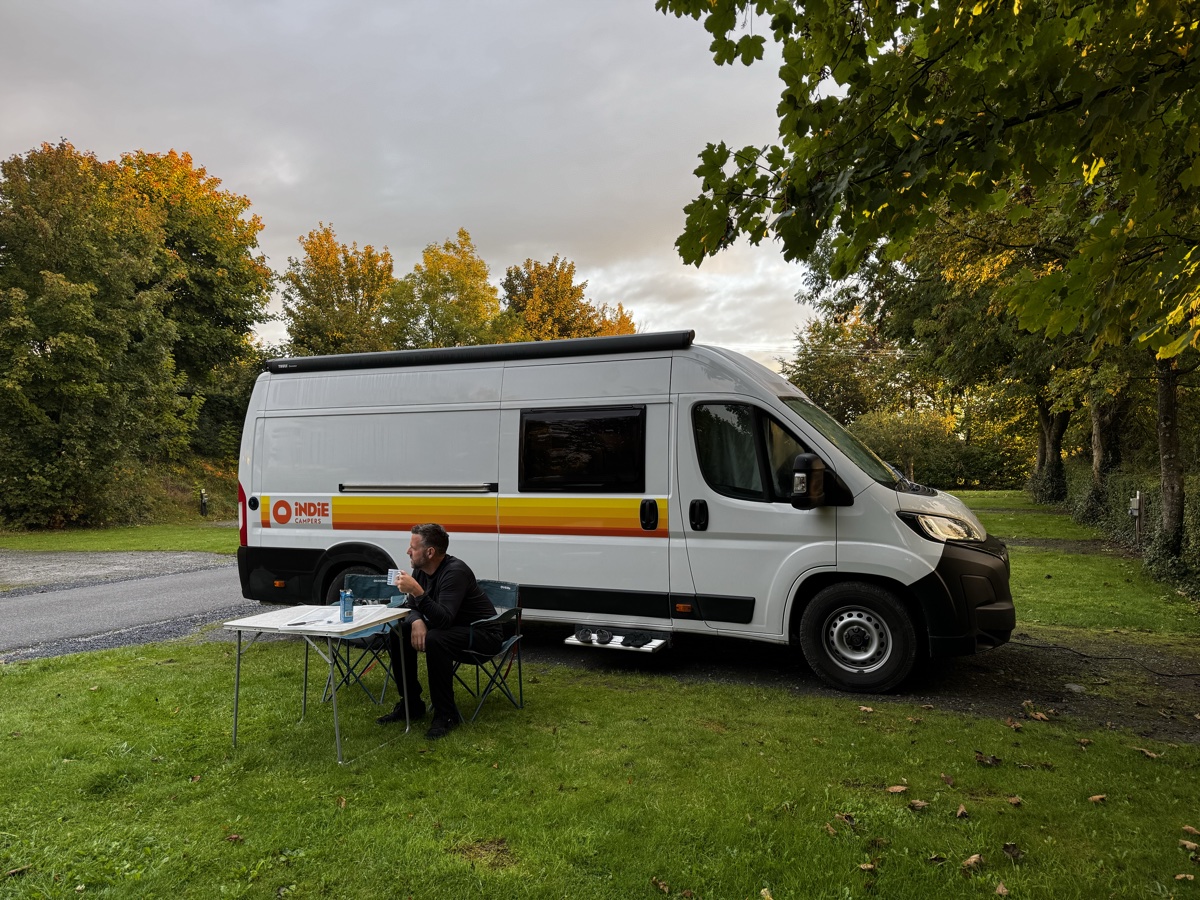 Camper van and traveler relaxing at campsite along R700 road in Ireland