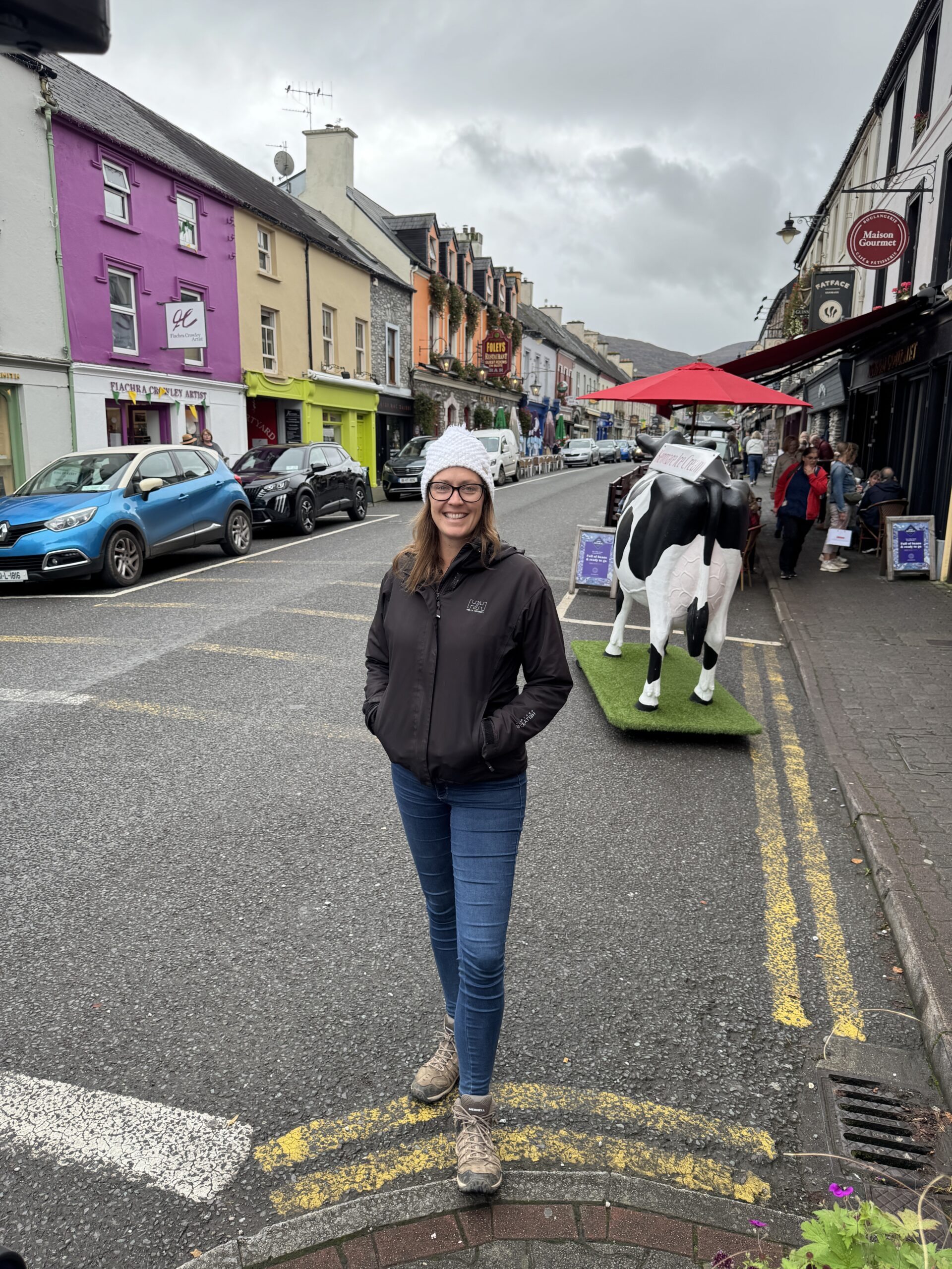 Woman standing on the colourful main street of Kenmare, County Kerry, Ireland