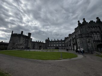 Kilkenny Castle exterior with grass courtyard under dramatic clouds