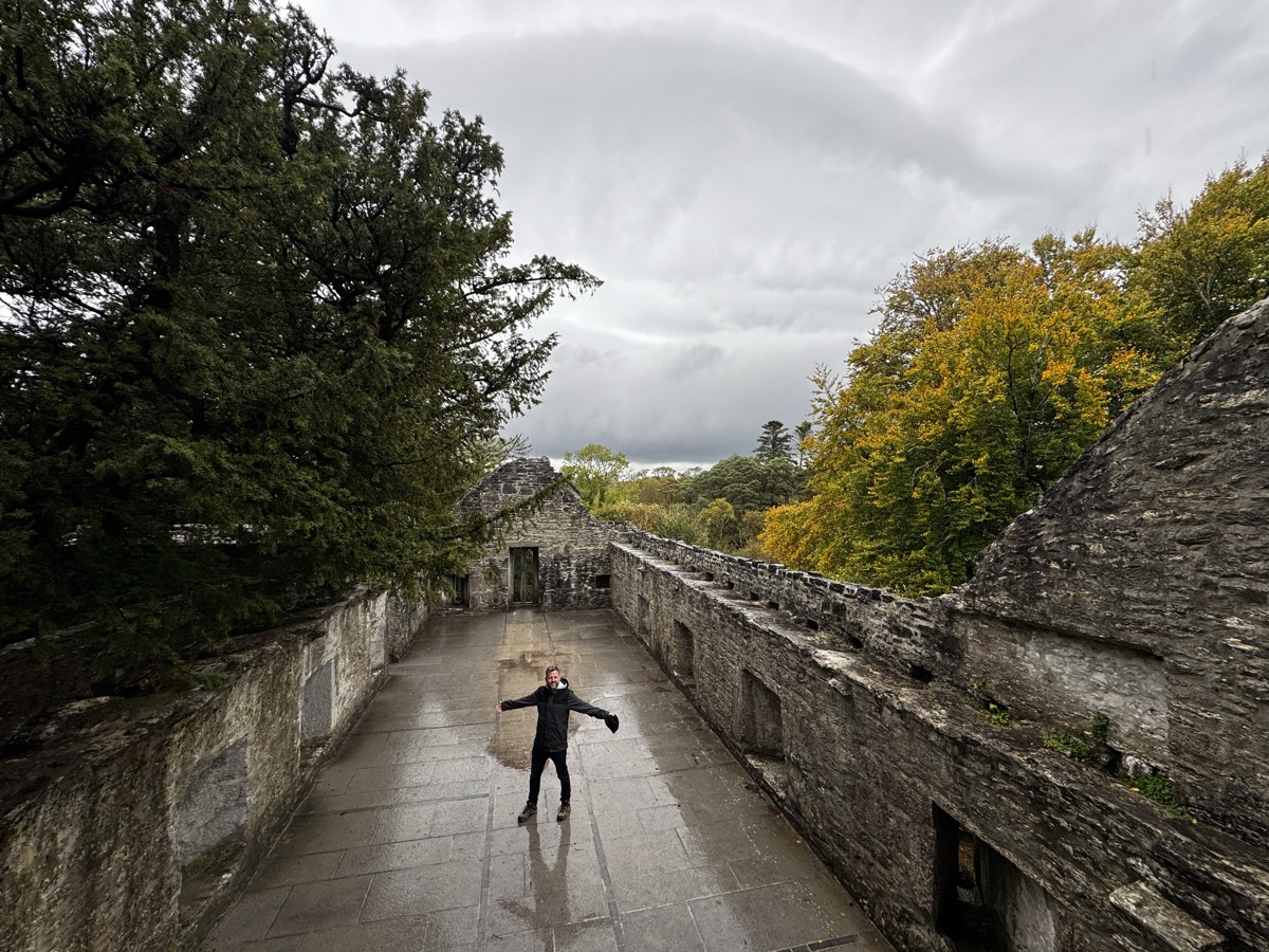 Person standing with arms wide on top of Muckross Abbey ruins in Killarney National Park
