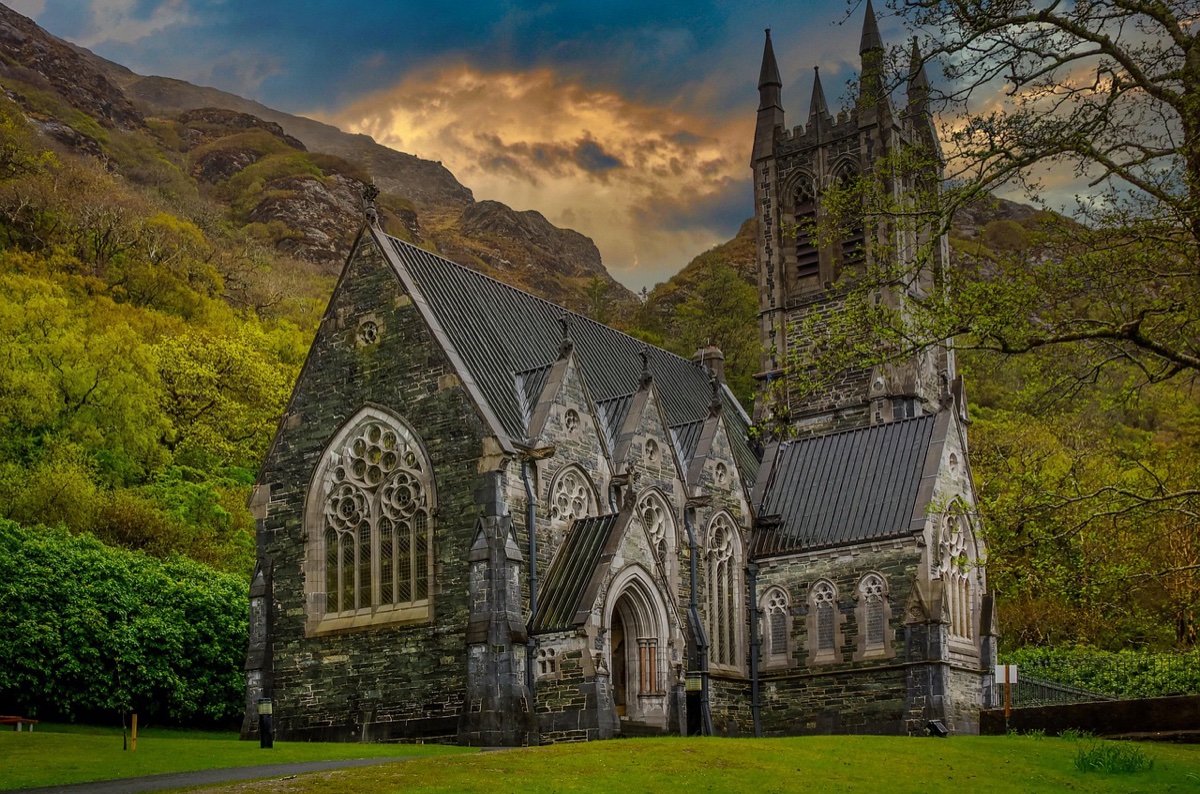 gothic stone chapel nestled against lush irish mountain slopes at dusk