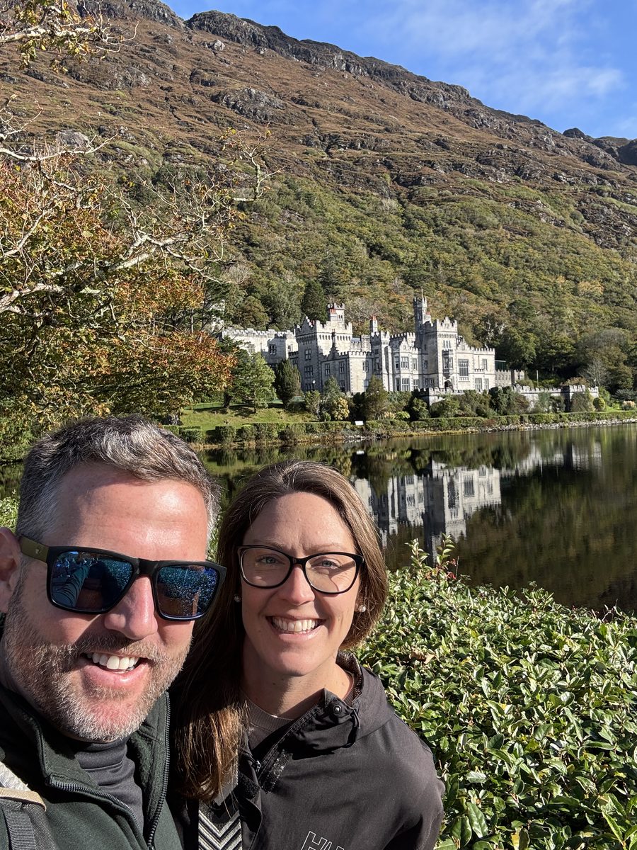 Nick and Dariece with Kylemore Abbey and its lake reflection behind them in Connemara, County Galway