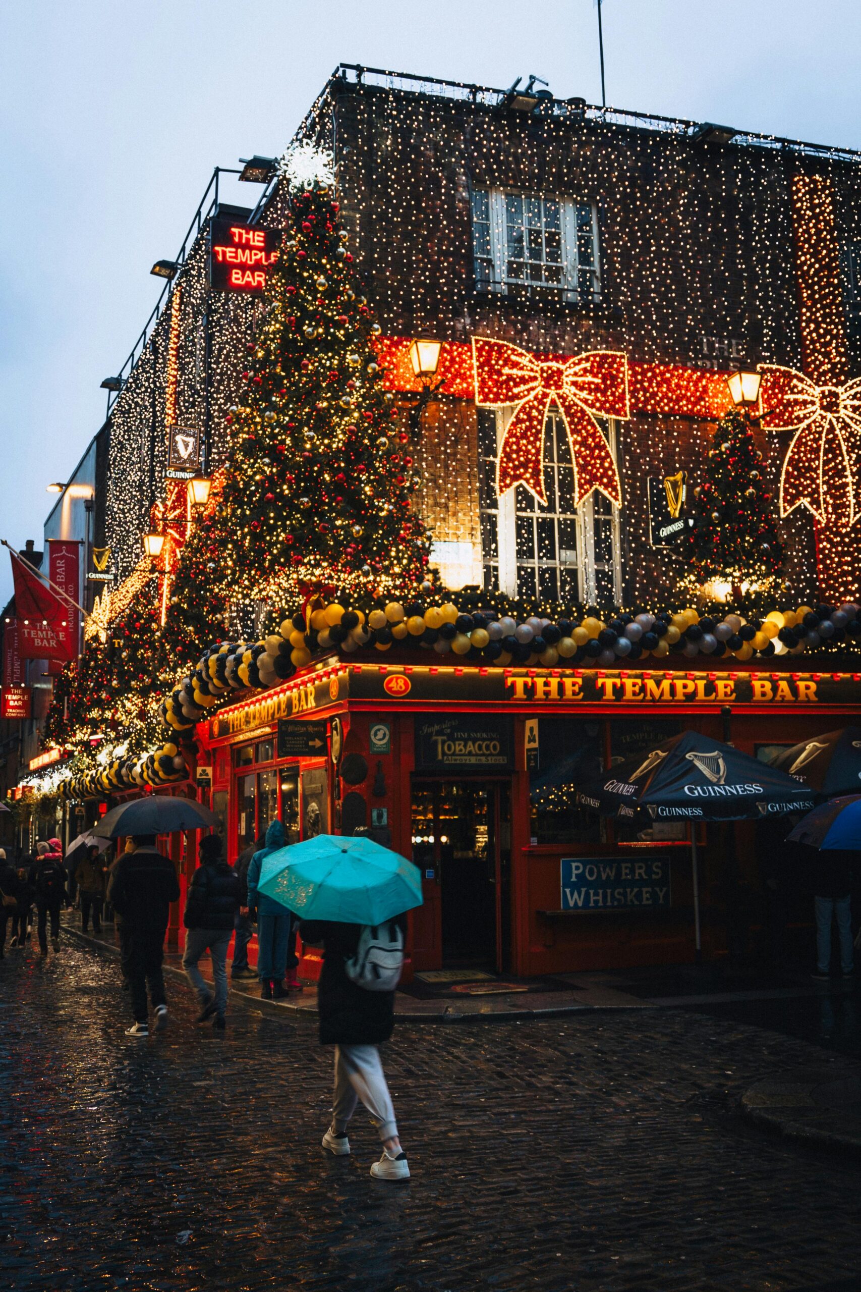 A vibrant scene of Dublin's Temple Bar, decorated with Christmas lights and festive cheer at night.