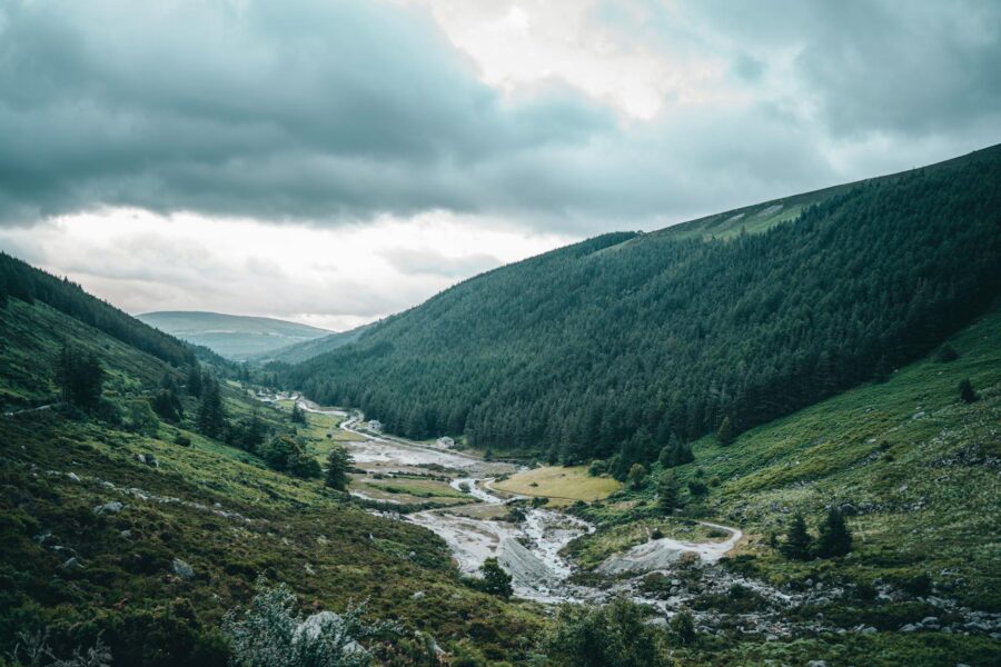 Scenic view of a lush valley and river in Wicklow, Ireland, under cloudy skies.