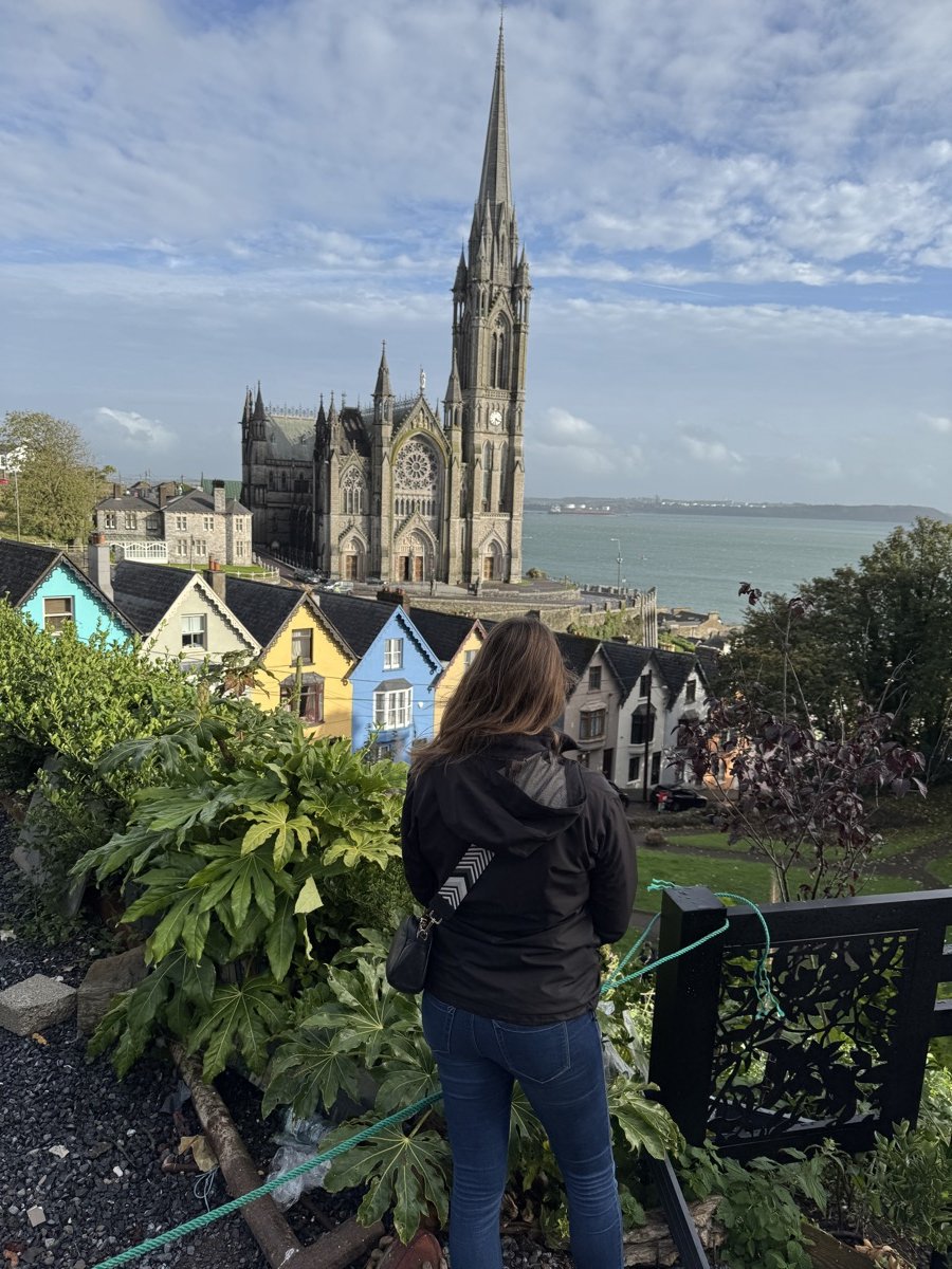 Woman overlooking St. Colman's Cathedral and Deck of Cards houses in Cobh, Ireland from Spy Hill