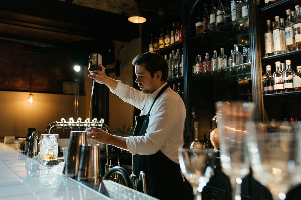 Bartender working behind a stocked pub bar