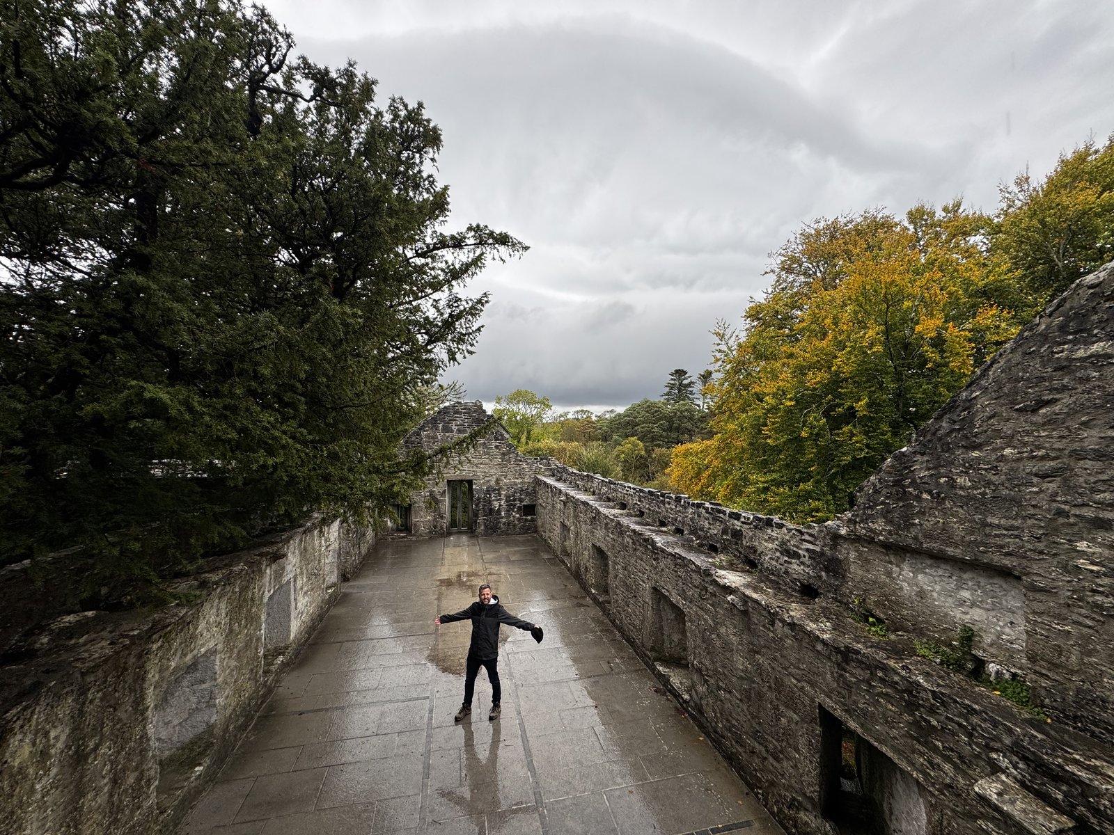 Nick standing inside a stone castle ruin in Kerry with green trees surrounding the abbey walls