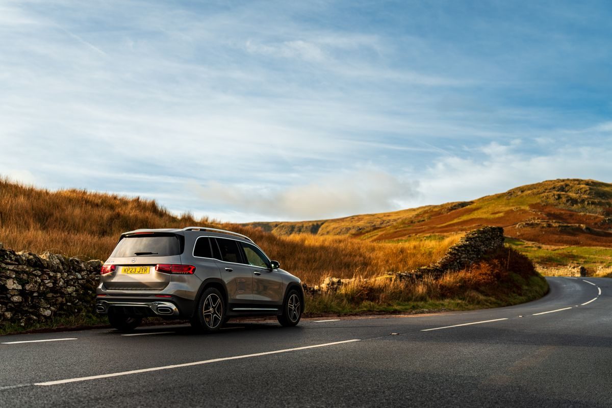 A car on a rural Irish road lined with stone walls