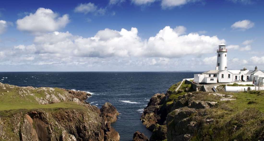Fanad Head Lighthouse standing white against the rocks on its peninsula