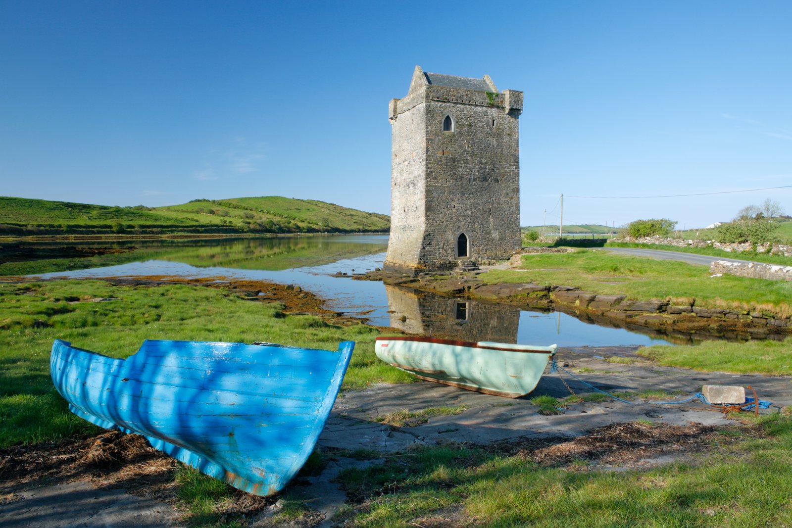 Stone tower house reflected in calm water near Clew Bay