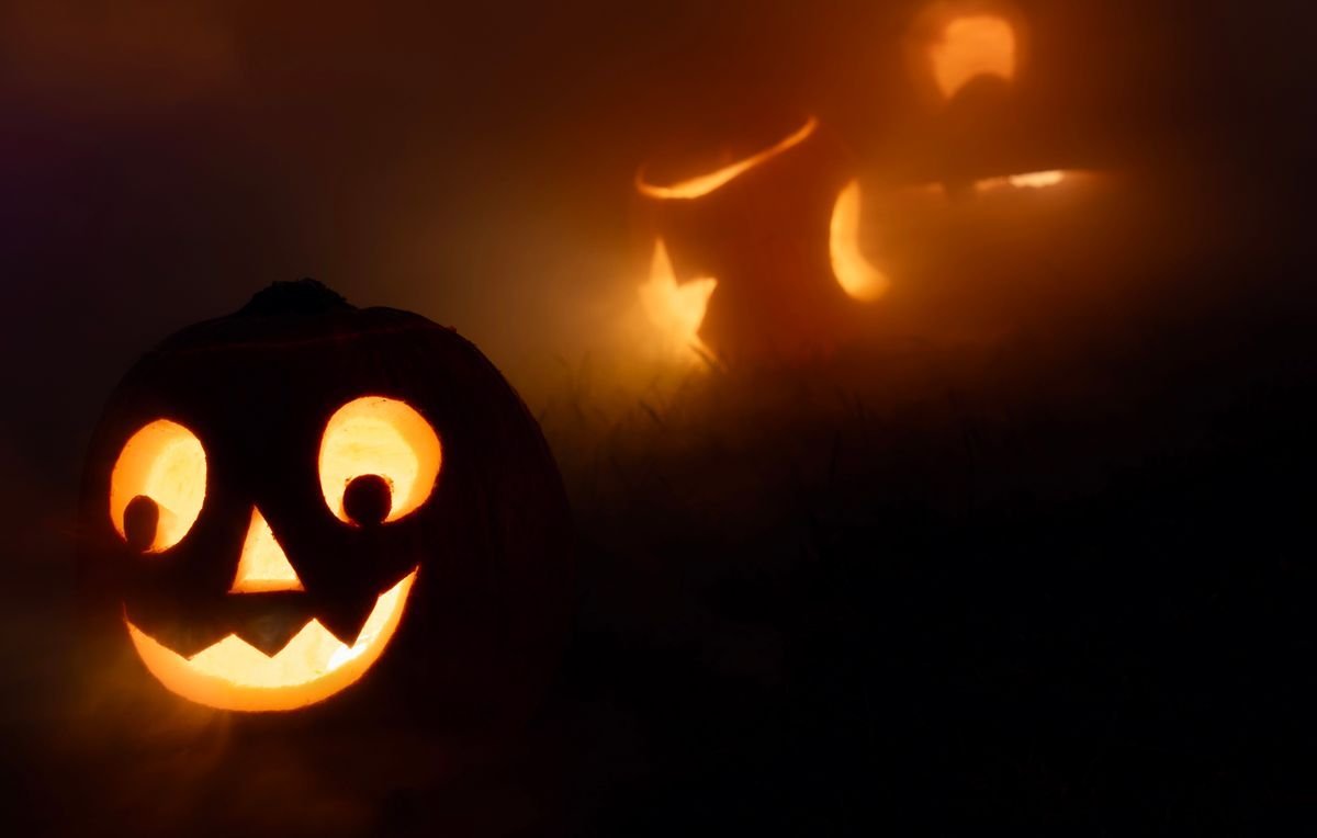 Glowing carved Halloween jack-o-lanterns in the fog at night