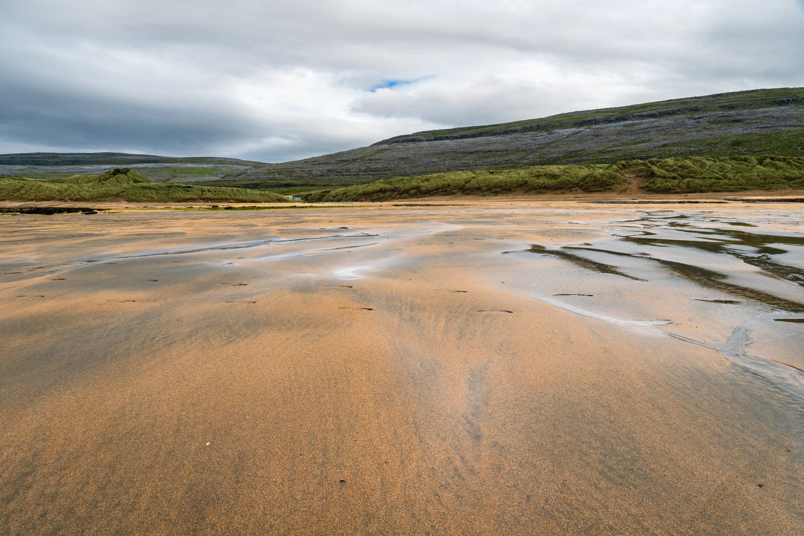 The wide open sand at Fanore Beach in County Clare, with the Burren hills behind it.
