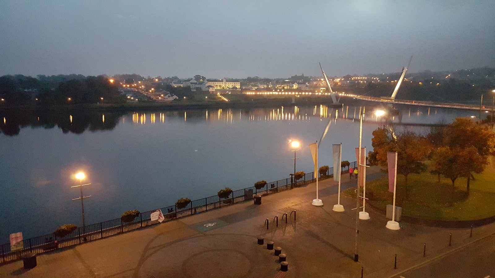 The Peace Bridge and Derry waterfront lit up at night over the Foyle