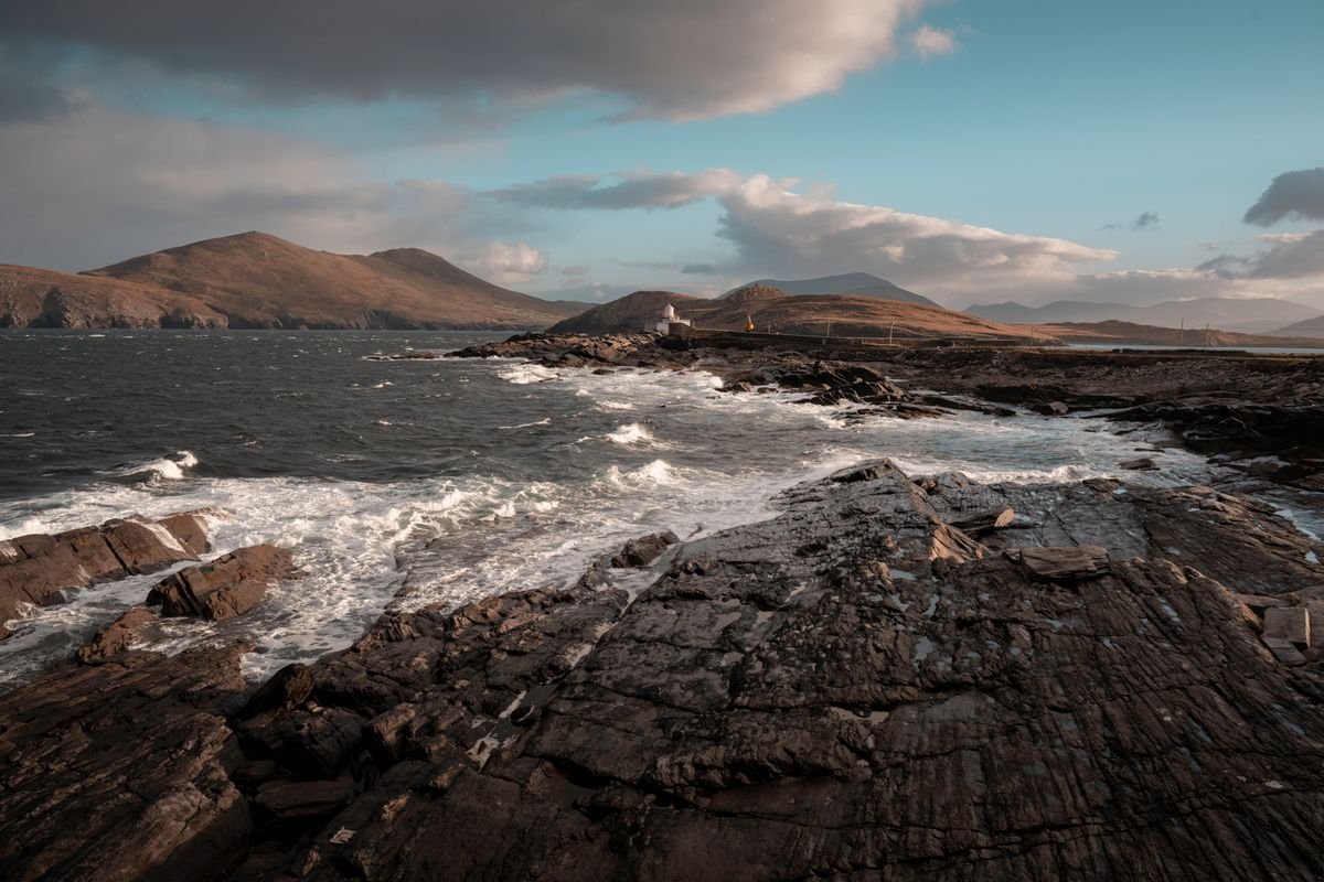 Rugged Kerry coastline at golden hour with waves and mountains