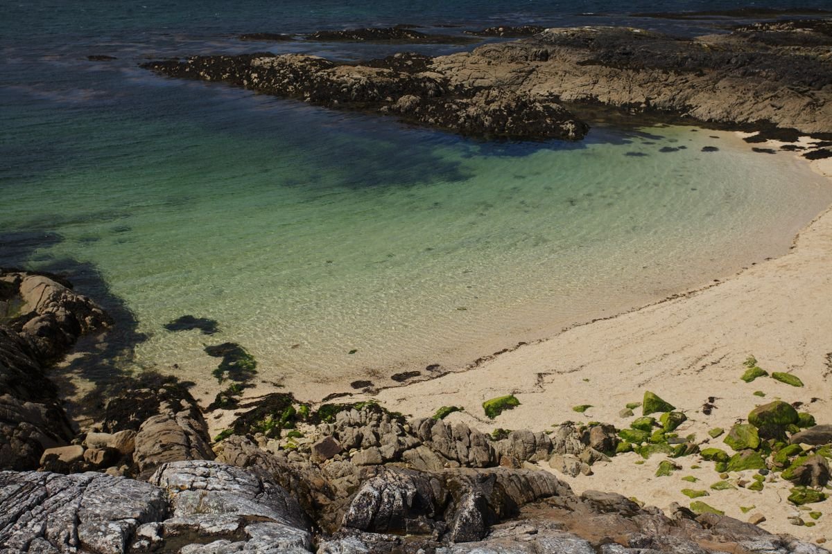 White sand and shallow turquoise water at a rocky cove on the Galway coast.