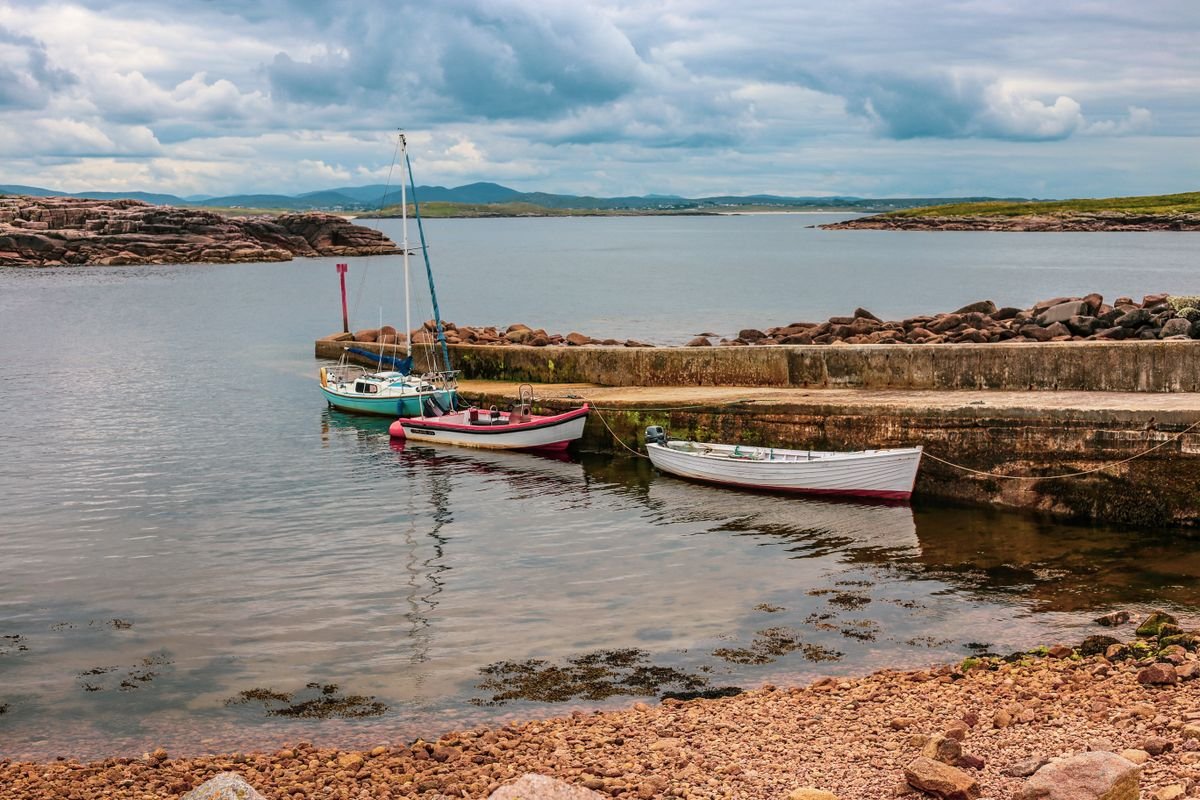 Small Donegal harbour with fishing boats moored beside a stone pier