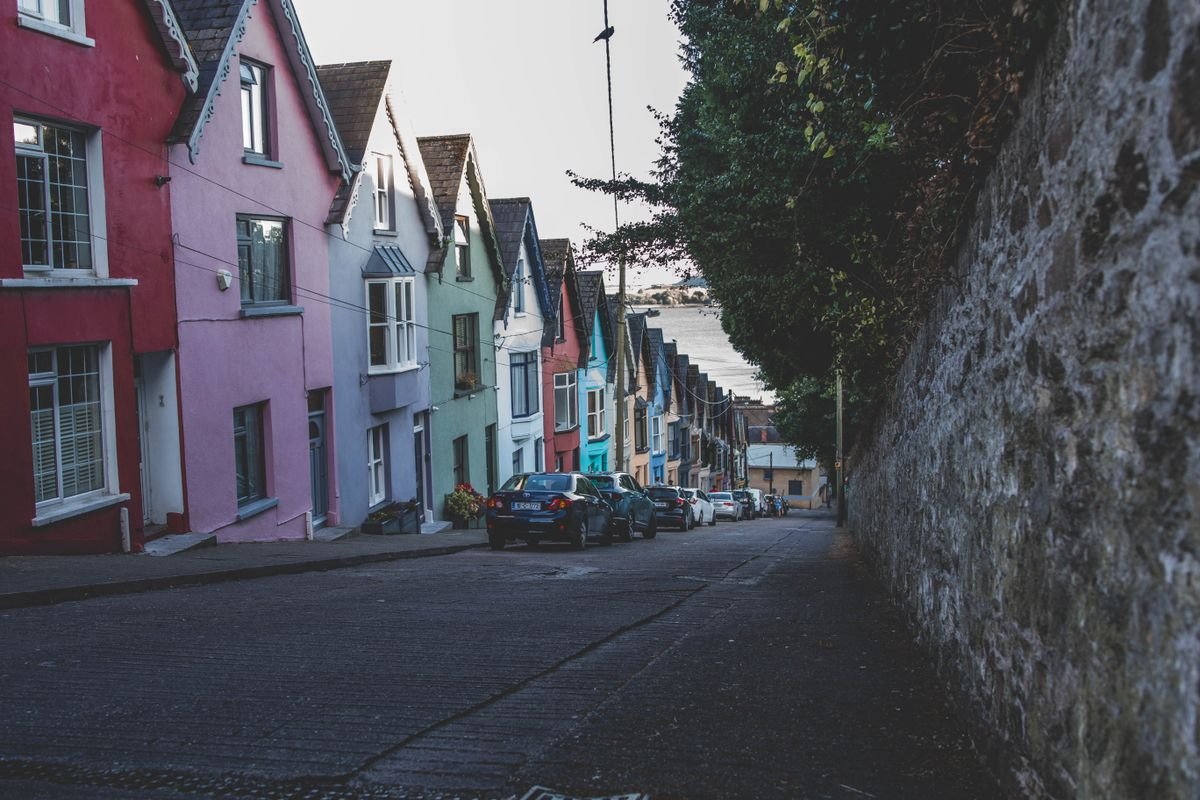 Row of colourful pastel terraced houses on a sloping street in Cork