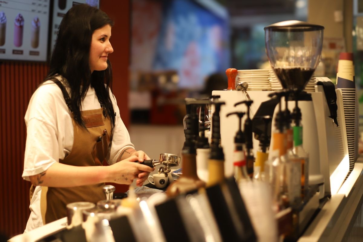 A barista pulling an espresso behind a cafe counter