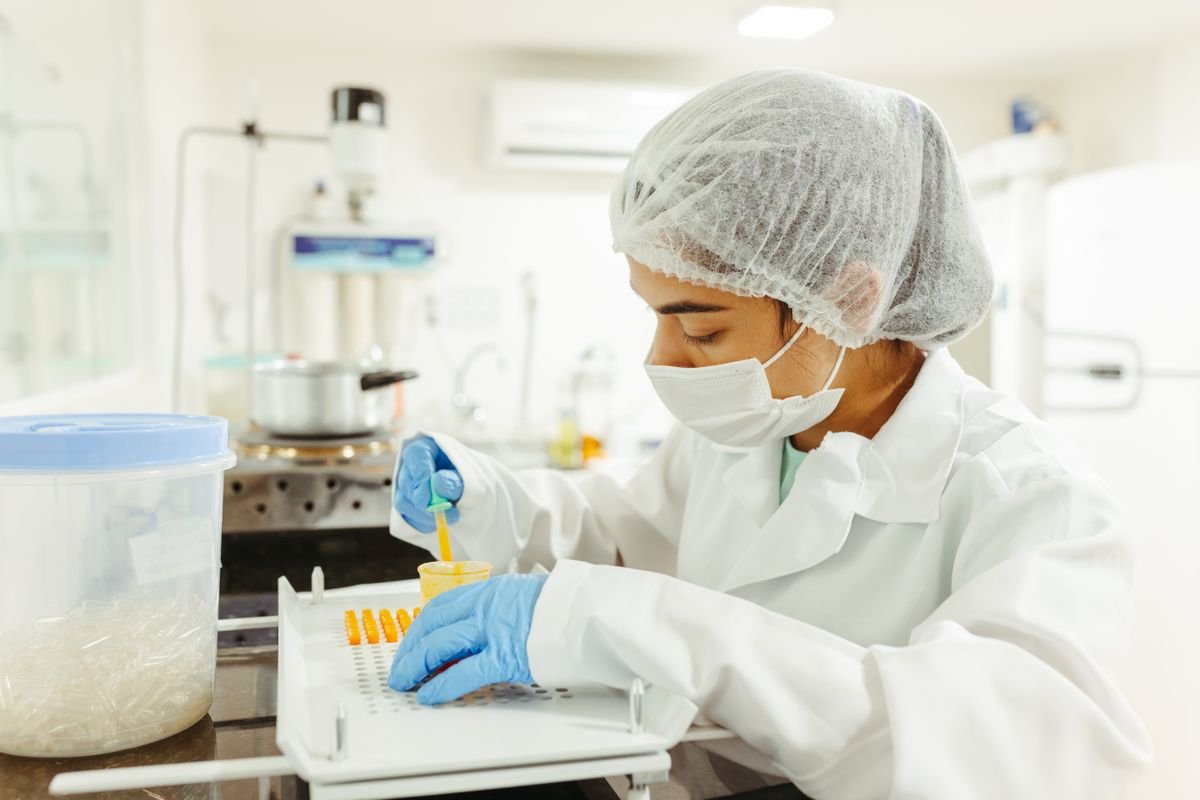 A lab technician in a white coat working in a pharmaceutical lab