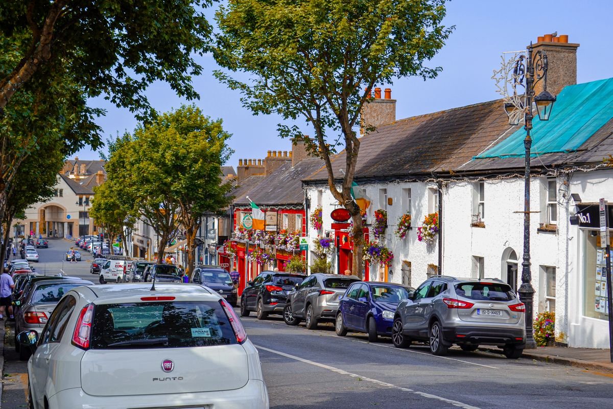 A colourful Irish village high street with a pub and parked cars