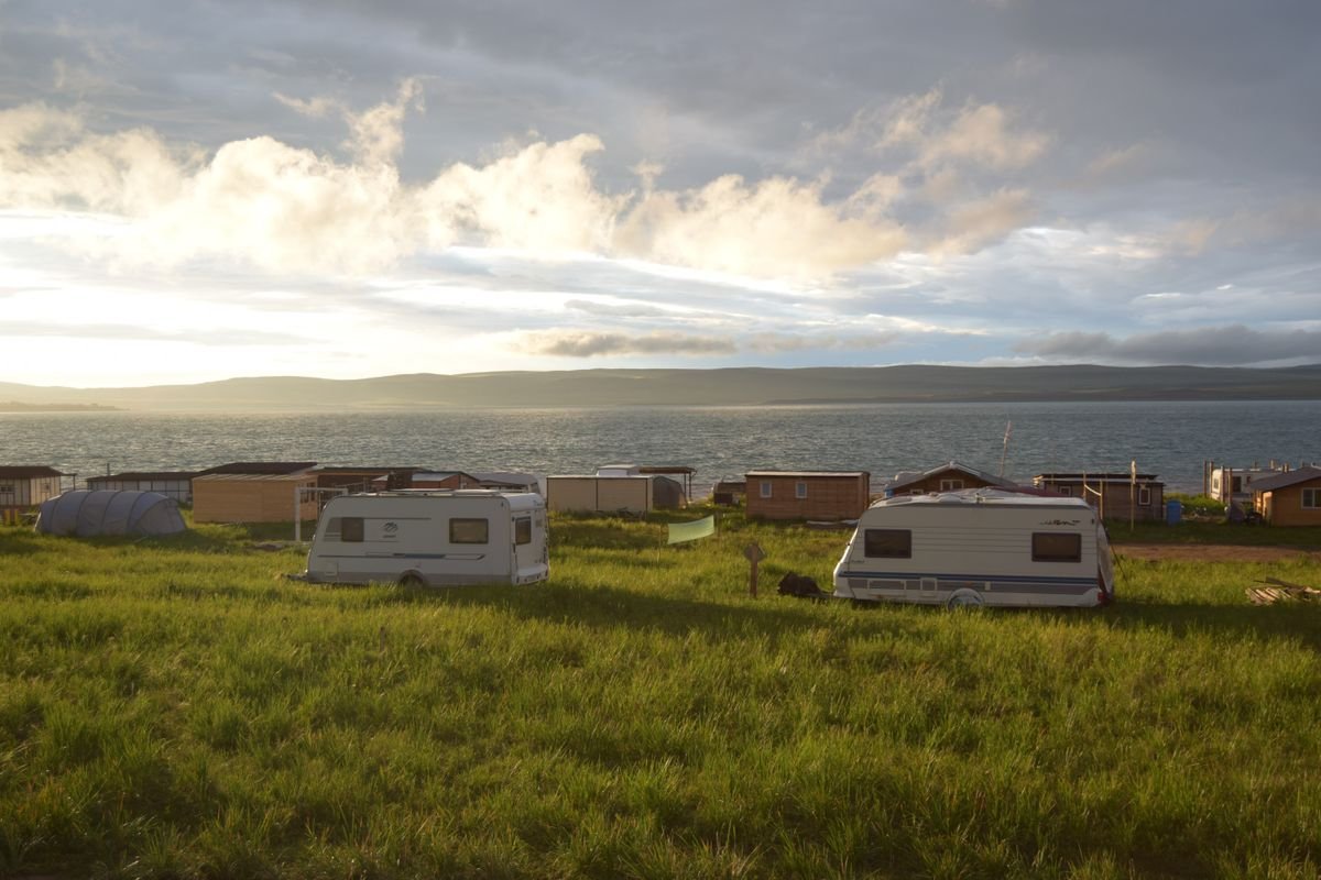 A campervan parked on grass beside the water at golden hour in Ireland