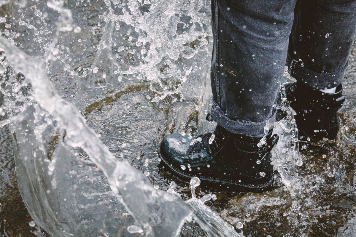 Waterproof boots splashing through water on a wet street