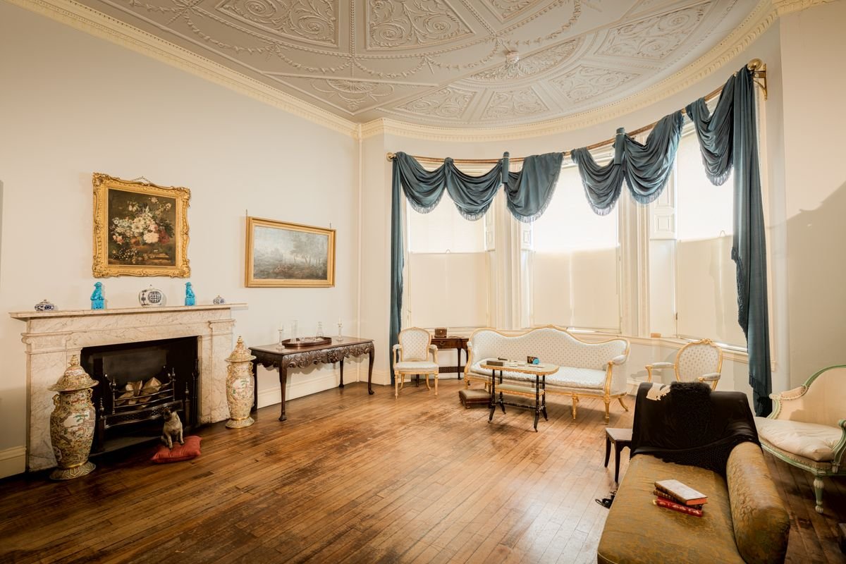 Period Victorian manor drawing room with marble fireplace and antique furniture