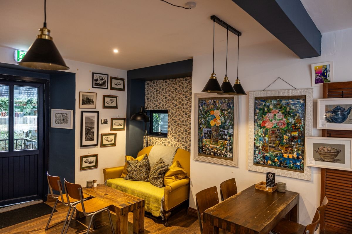 A cosy guesthouse sitting room with a yellow sofa and art on the walls