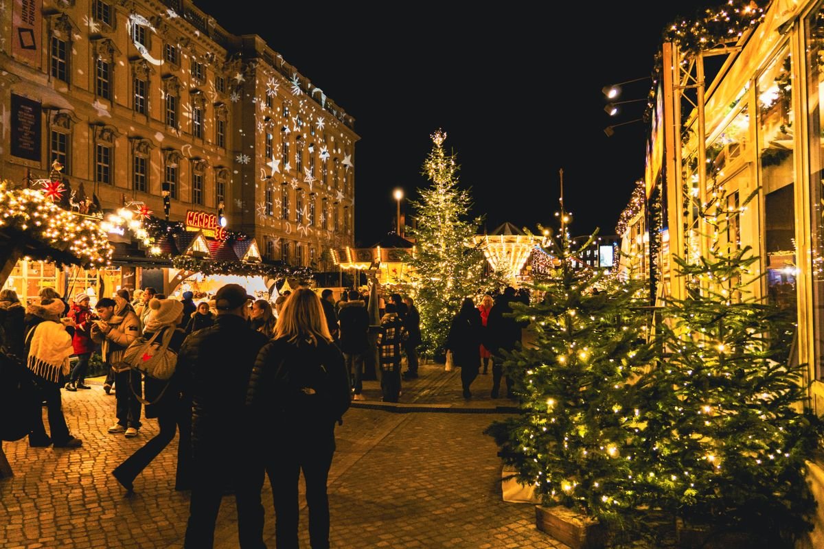 A Christmas market at night with lit stalls and a tall lit tree
