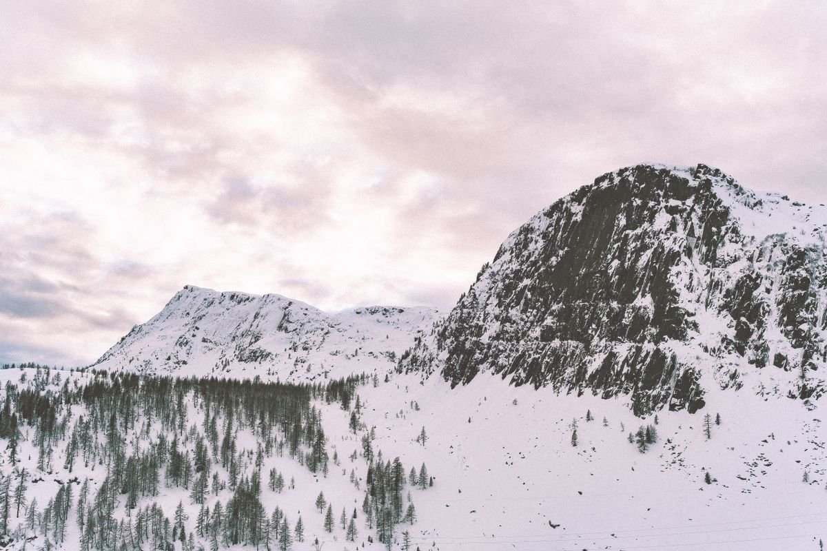 Snow on rocky mountain tops under a moody winter sky